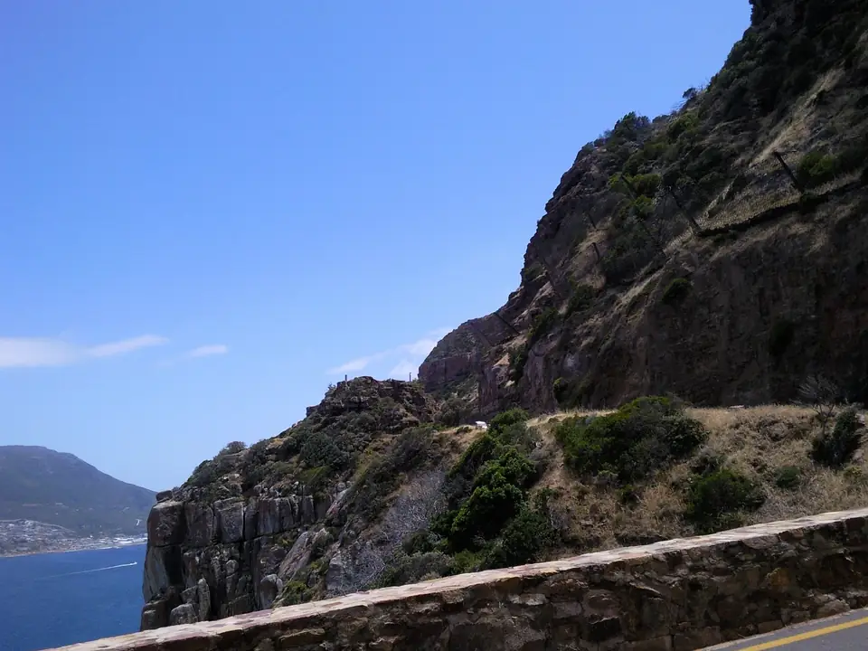 Schmale Küstenstraße zwischen einer steilen Felswand und dem Meer