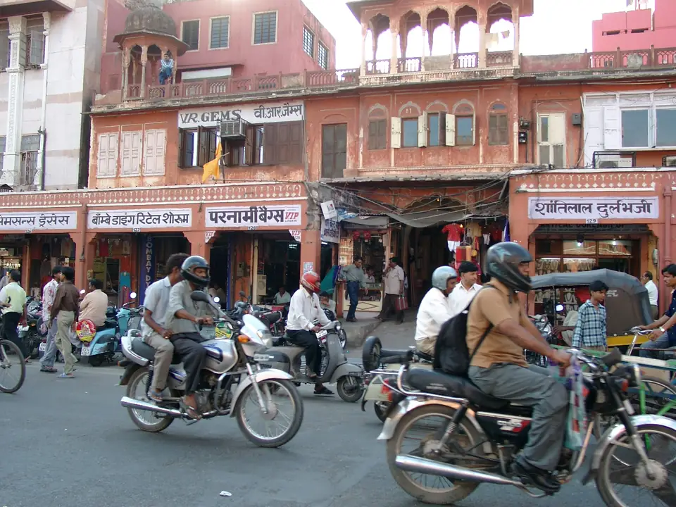 Motorräder und eine Fahrradrikscha vor Geschäften in der rosafarbenen Altstadt von Jaipur