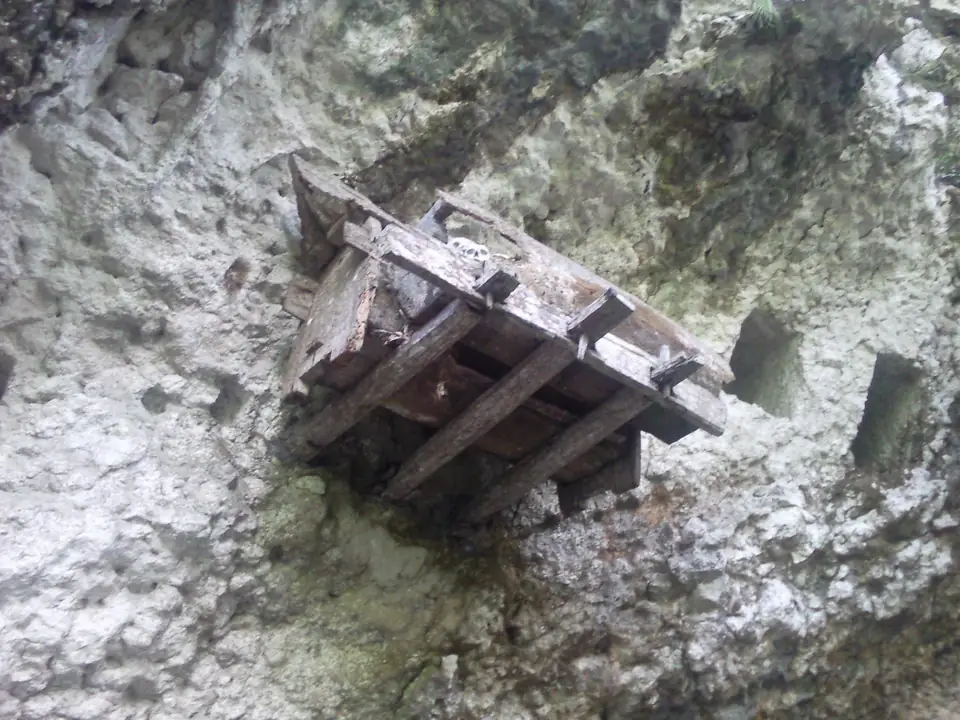 Alte hölzerne Särge an einer überhängenden Felswand