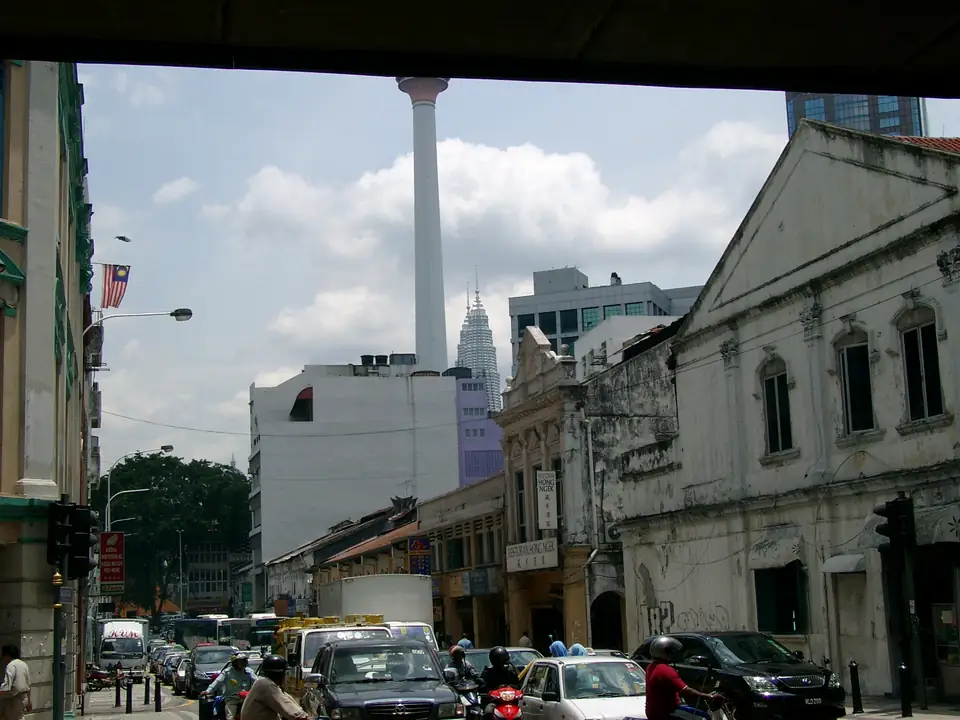 Verkehr und alte Geschäftshäuser an der Jalan Tun H. S. Lee, dahinter Menara KL und eine Spitze der Petronas Towers