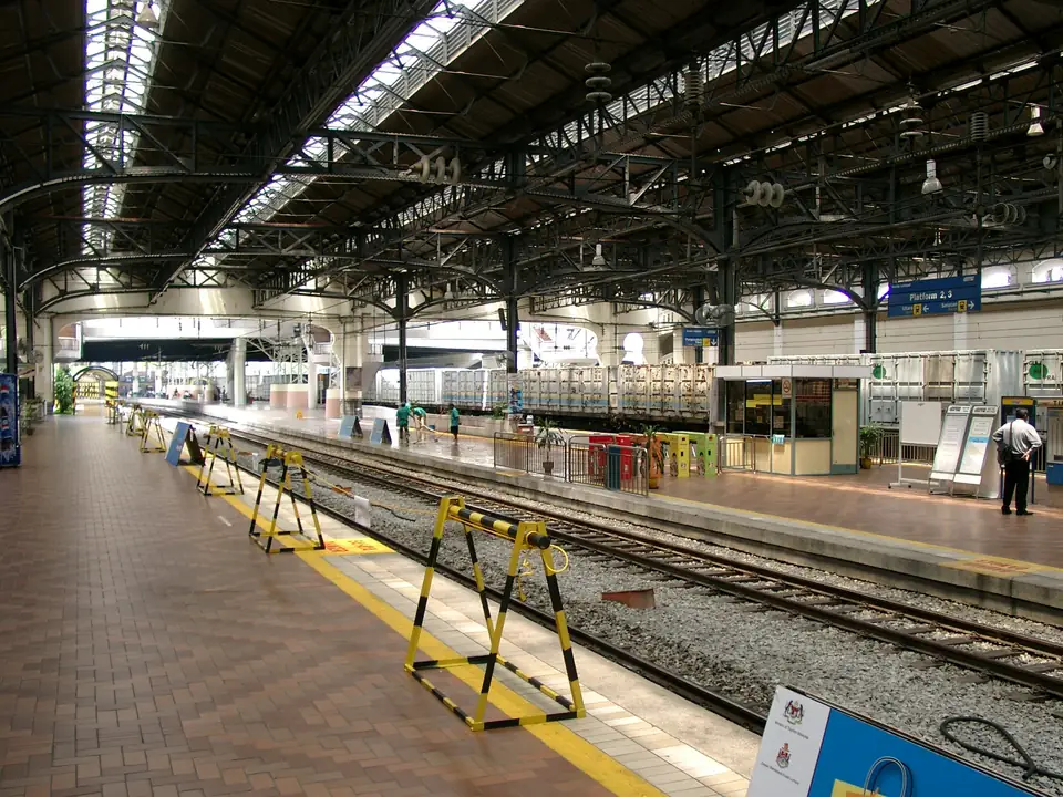 Bahnsteige mit Güterzug und wenigen Menschen unter der historischen stählernen Bahnhofshalle