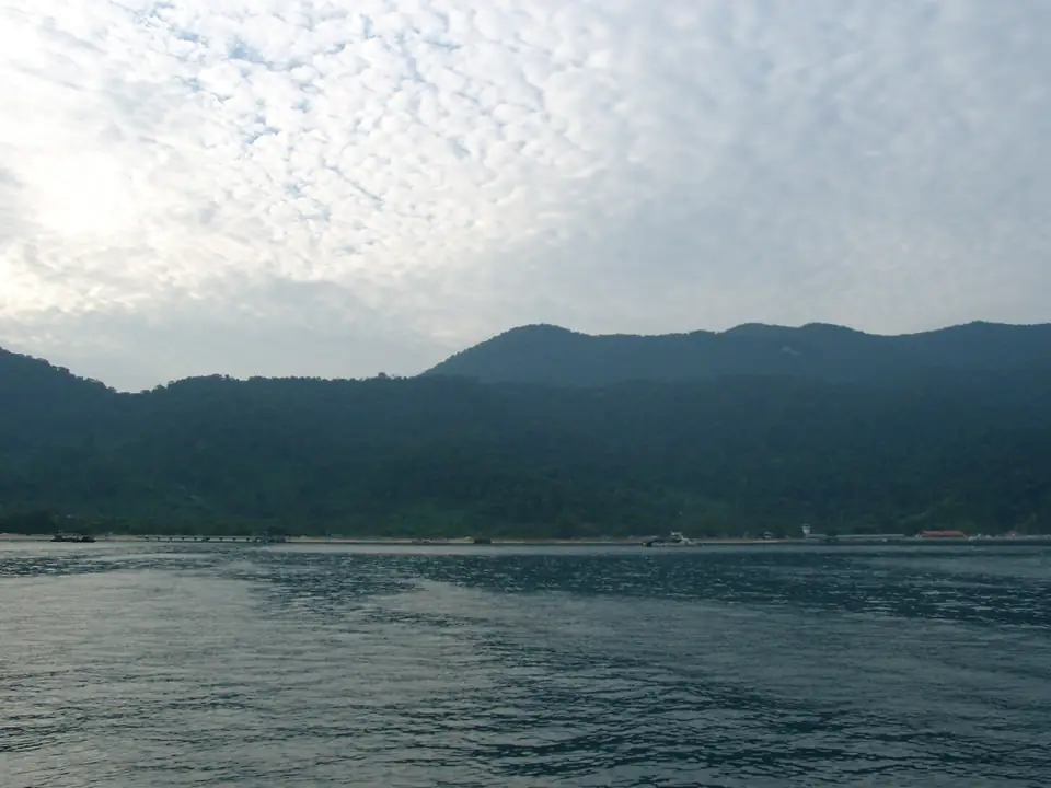 Blick vom Wasser auf eine dicht bewaldete tropische Insel
