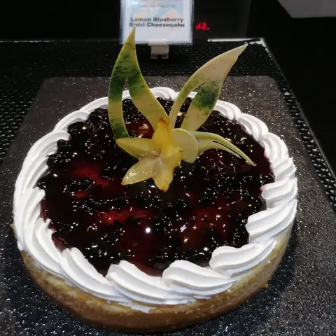 Runde Torte mit dunklem Fruchtbelag, Sahnerand und Obstdekoration am Buffet