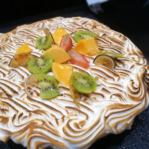 Mit hellen Baiserwellen, Kiwi und Zitrusfrüchten dekorierte Torte