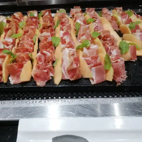 In Reihen angerichtete Schinken-Melonen-Häppchen am Buffet