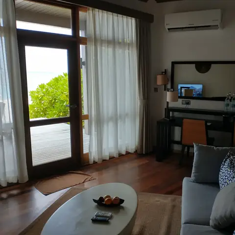 Wohnbereich der Villa mit Sofa, Obstschale und Terrassentür zum Strand