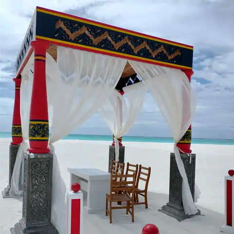 Bunt gestalteter Hochzeitspavillon mit weißen Vorhängen am Strand