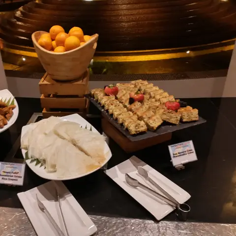 Dessertbuffet mit Kuchenstücken, einer Schale Obst und Beilagen