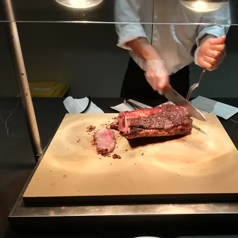 Koch beim Aufschneiden eines Bratens an einer Buffetstation