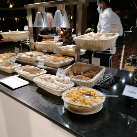 Mehrere Schalen mit warmen Gerichten und ein Koch an der Buffetstation