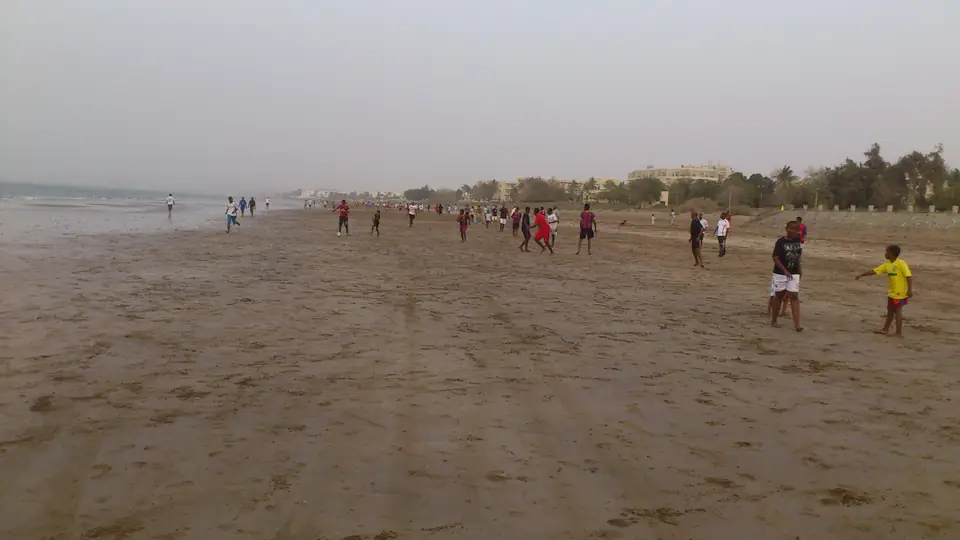Mehrere Gruppen spielen auf dem breiten Sandstrand Fußball