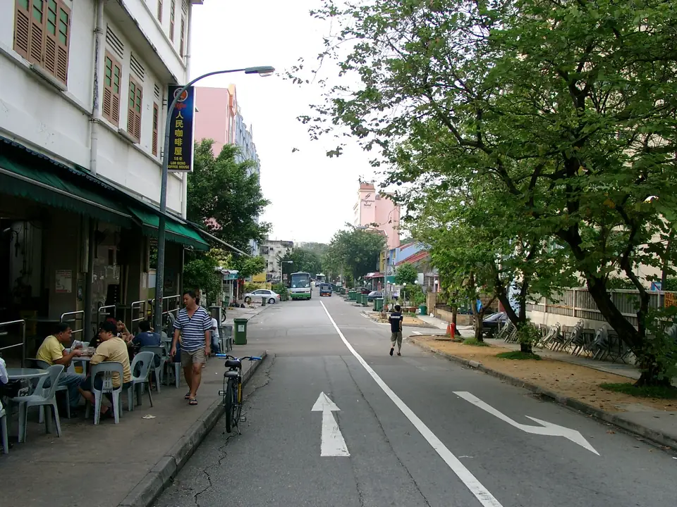 Straßenlokal mit Tischen auf dem Gehweg und mehrgeschossige Hotelhäuser in Geylang