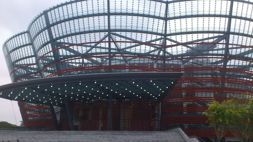 Geschwungene Fassade des Nelum Pokuna Theatre mit Glaslamellen, roten Bändern und beleuchtetem Eingang