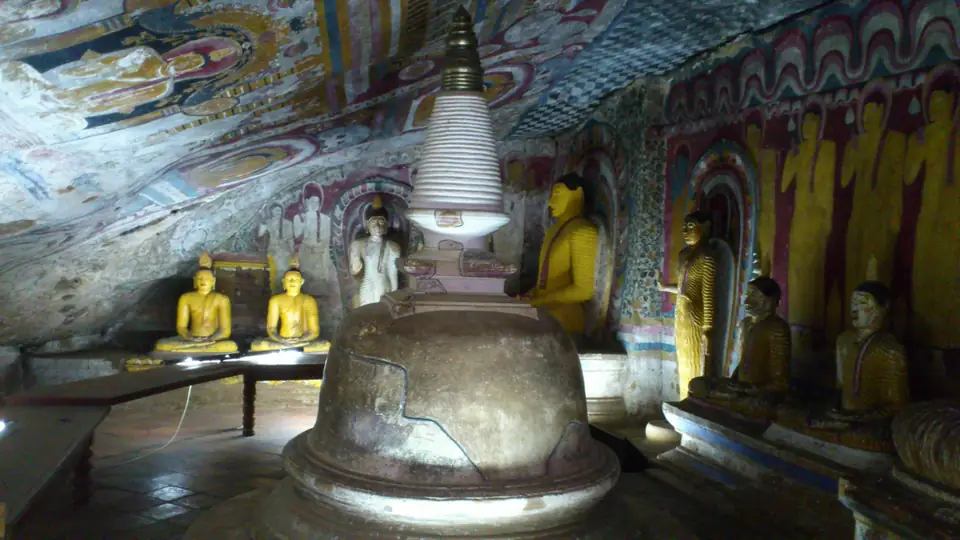 Kleine Stupa und Buddhafiguren unter vollständig bemalten Höhlenwänden und Decken