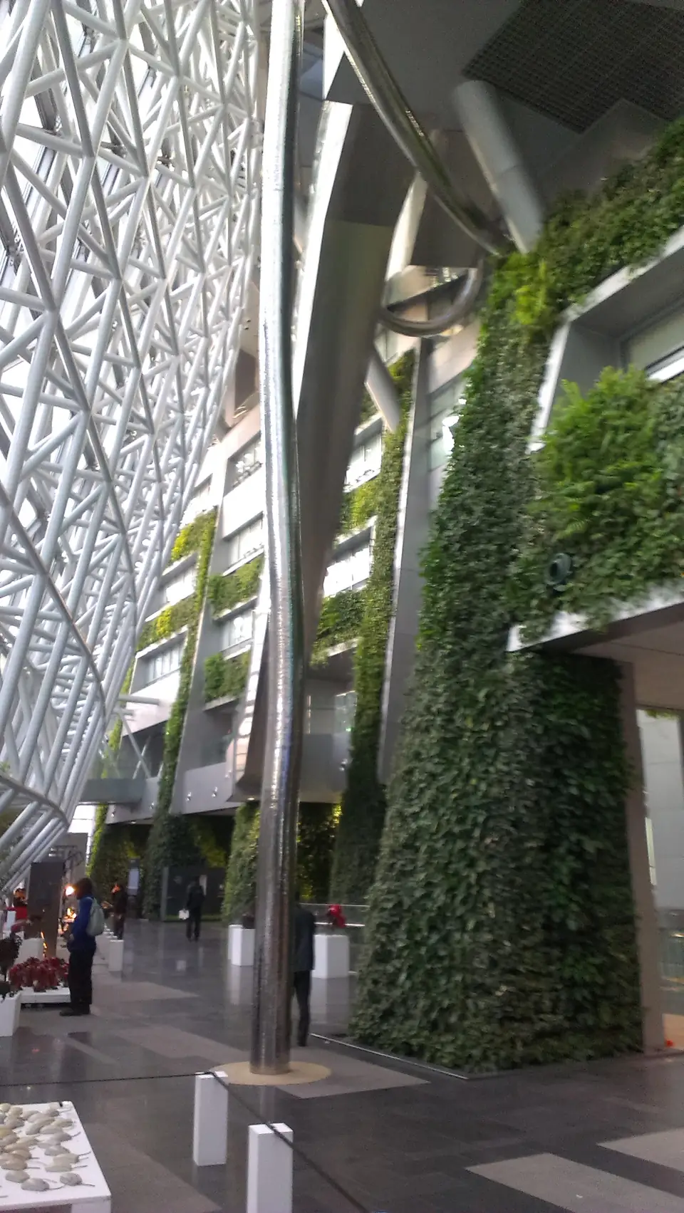 Glasdach und begrünte Innenwände in einem hohen Atrium