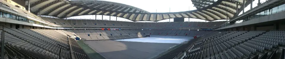 Panorama der überdachten Stadionränge und des teilweise verschneiten Spielfelds
