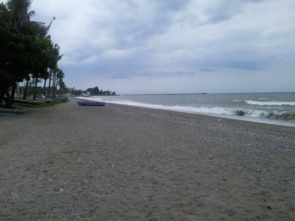 Küstenstraße und dunkler Strand unter einem wolkenverhangenen Himmel
