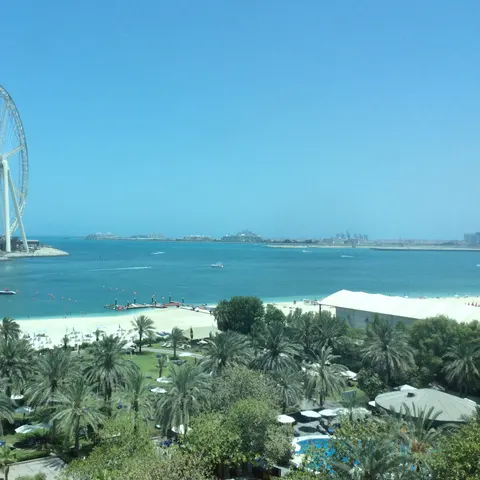 Blick über Palmengarten und Strand des Sheraton auf das Meer und das Riesenrad Ain Dubai, dessen Rad noch ohne Gondeln ist