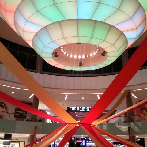 Mehrgeschossiges Atrium der Dubai Mall mit farbig beleuchteten Deckenringen und roten und orangefarbenen Dekorationsbändern
