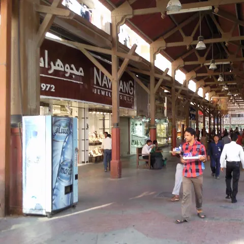 Überdachte Gasse im Deira Gold Souk mit Holzstützen, Schmuckgeschäften und Passanten