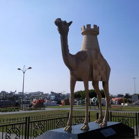 Kamelskulptur mit einem steinernen Turm auf dem Rücken vor dem Hafenbereich am Dubai Creek