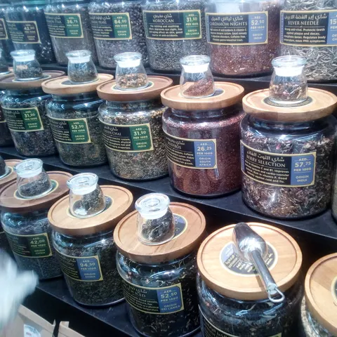 Große Gläser mit losen Tees und Kräutern, Holzdeckeln und kleinen Probengläsern im Supermarkt