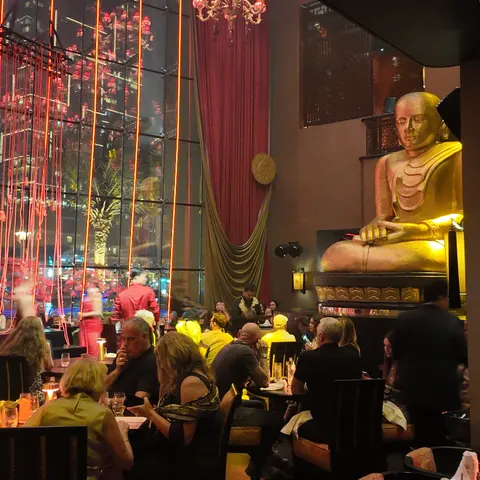 Große goldene Buddha-Statue neben der Fensterfront und den besetzten Restauranttischen der Buddha-Bar Dubai