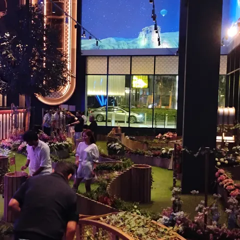 Gäste auf den Minigolfbahnen bei Swingers Dubai zwischen Blumen, Holzbegrenzungen und farbiger Beleuchtung