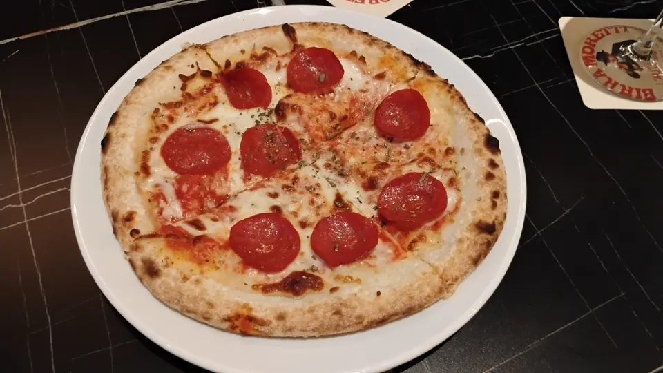 Pizza mit Käse und Salamischeiben auf einem weißen Teller bei Swingers Dubai