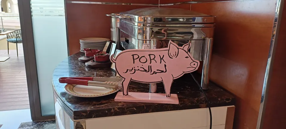 Separater Buffetbereich mit Warmhaltebehälter und einem Schweineschild mit der Aufschrift Pork