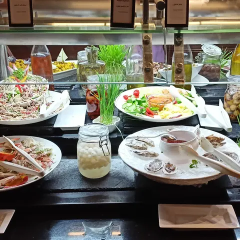 Salate und kalte Vorspeisen auf weißen Platten unter dem Glasschutz des Buffets