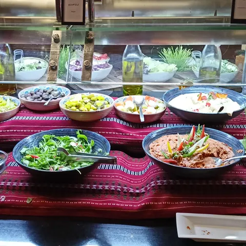 Verschiedene Salate in Schüsseln auf einem rot karierten Tuch am Buffet