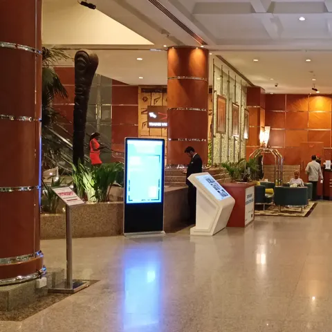Lobby-Eingang mit rotbraunen Säulen, Steinboden und Blick zum Empfang