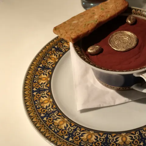 Dessert in einer Tasse auf einer blau-golden ornamentierten Untertasse, dazu Gebäck und goldfarbene Dekoration