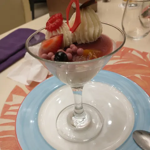 Dessert im hohen Glas mit Erdbeeren, verschiedenen Cremes und einer roten Dekoration