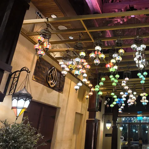 Zahlreiche bunte Mosaiklampen hängen zwischen dunklen Holzbalken im Souk Madinat Jumeirah