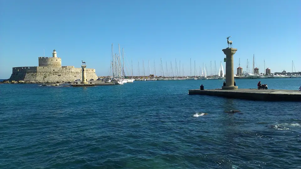 Hafeneinfahrt mit Hirschsäulen, Segelbooten und einer steinernen Festung