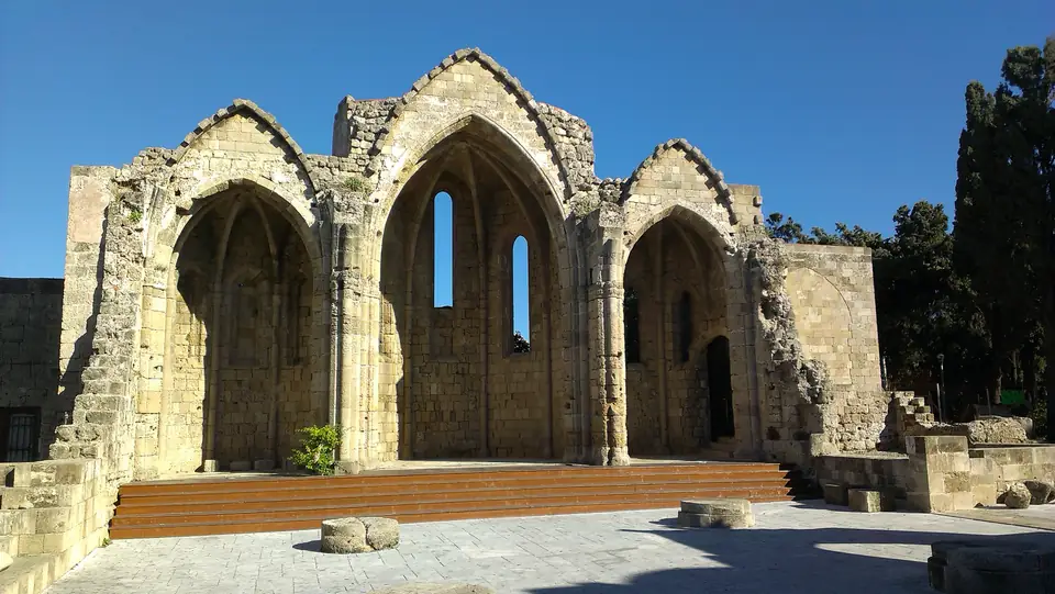 Drei gotische Apsiden einer dachlosen Kirchenruine unter blauem Himmel