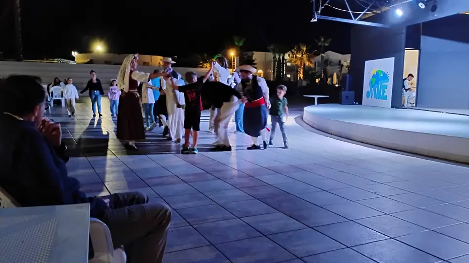 Eine Gruppe tanzt am Abend auf der beleuchteten Veranstaltungsfläche des Hotels vor sitzenden Zuschauern