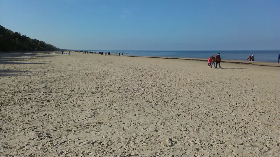 Breiter Sandstrand mit Spaziergängern an der ruhigen Ostsee