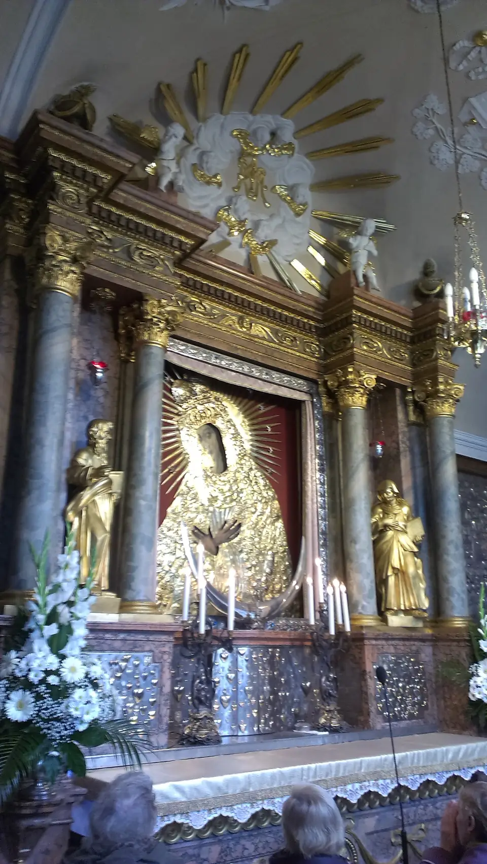 Marienbild mit vergoldeter Verkleidung zwischen Säulen und Kerzen auf einem verzierten Altar
