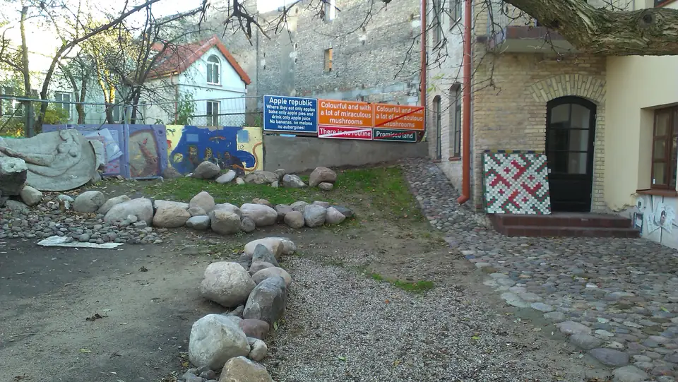 Künstlerisch gestalteter Hof mit Felssteinen, Wandbildern und bunten Schildern