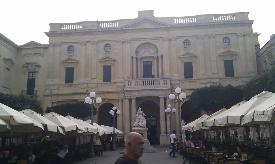 Historische Bibliotheksfassade hinter einem Platz mit Café-Schirmen
