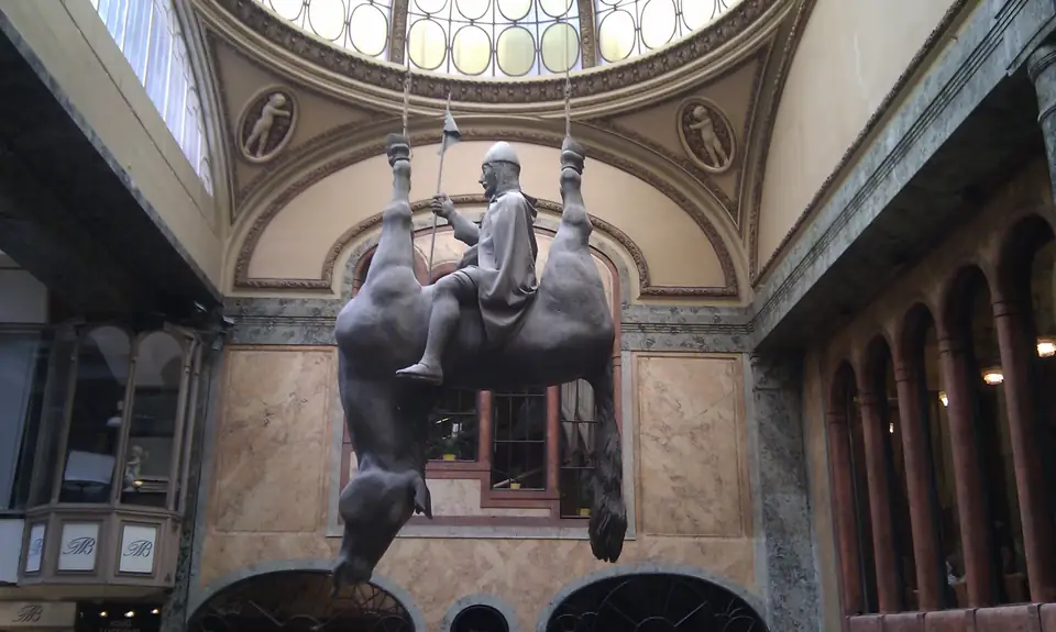 Reiterfigur auf dem Bauch eines kopfüber aufgehängten Pferdes unter der Glaskuppel einer Passage