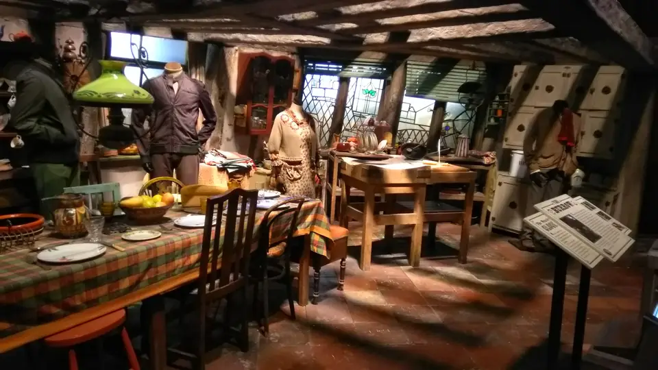 Filmset der Weasley-Küche mit einem gedeckten Esstisch, grünen Stühlen, Küchenutensilien und Figuren