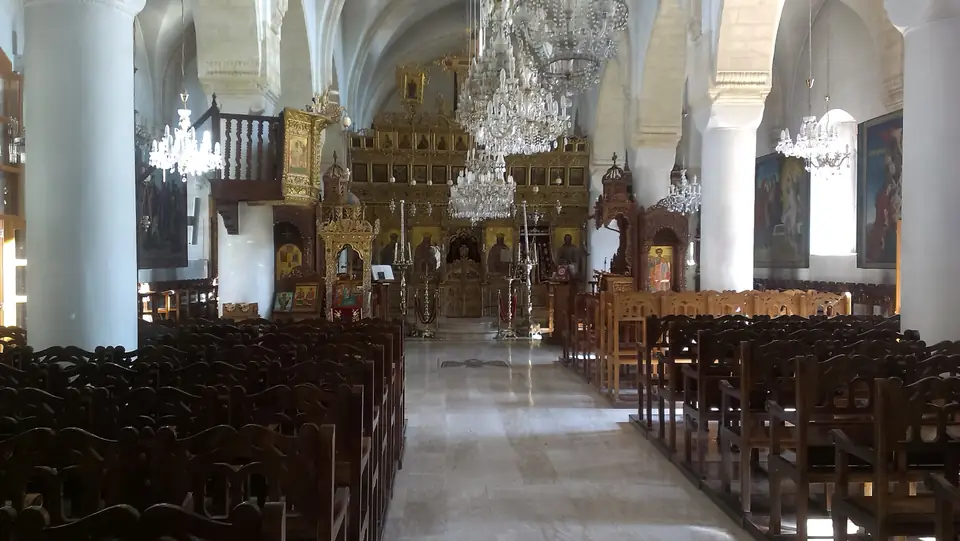 Weißes Kirchengewölbe mit Kronleuchtern, Holzgestühl und vergoldeter Ikonostase