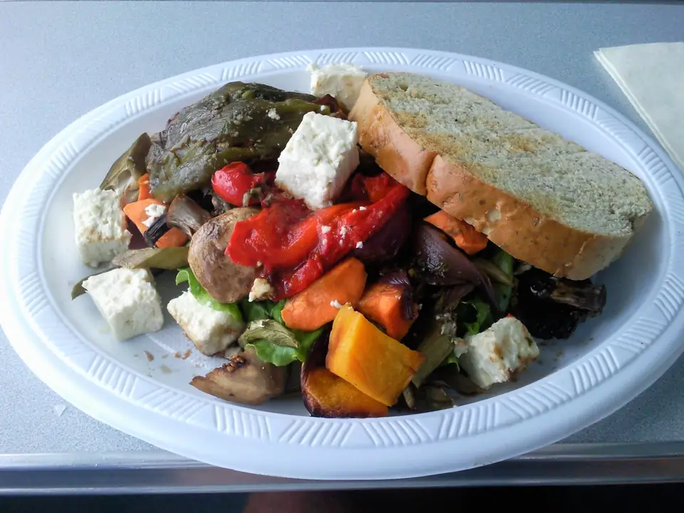 Antipasti-Salat mit Gemüse, weißen Käsewürfeln und Brot auf einem Teller