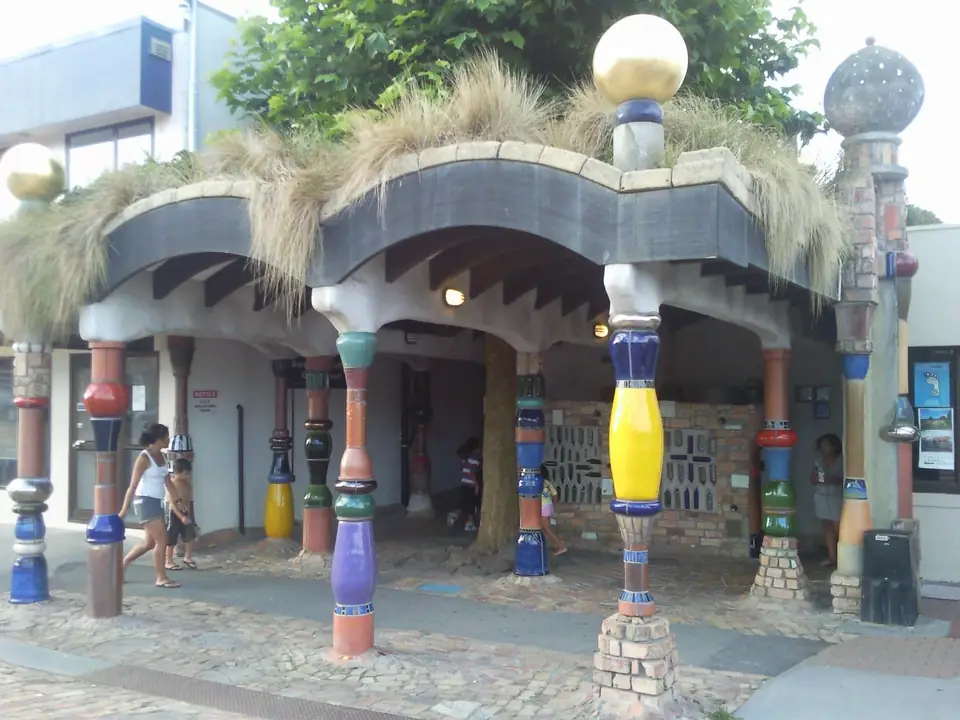 Öffentliche Hundertwasser-Toiletten mit bunten Säulen, welligem Dach und Pflanzen
